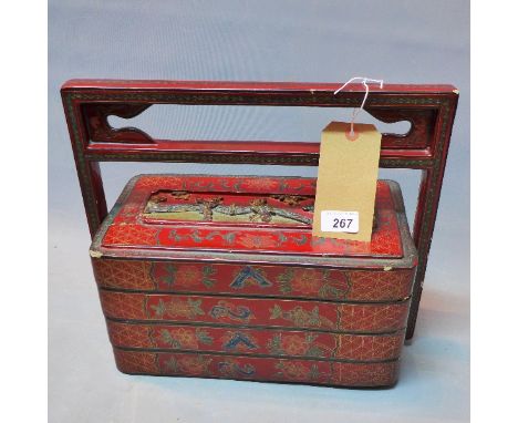 A red lacquered Chinese food carrier, having three containers and carrying handle, decorated with a panel of children playing