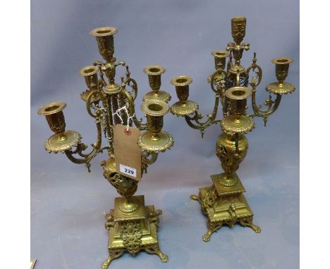 A pair of early 20th century four branch, five light polished brass candelabras, on urn support and stepped bases having drag