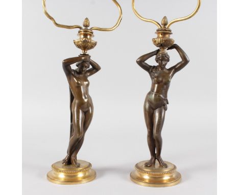 A PAIR OF 19TH CENTURY FRENCH LAMPS of NUDE YOUNG LADIES holding light fittings, on a circular base. 12ins high.