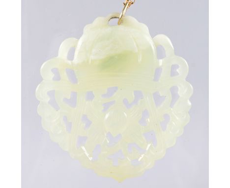 A CARVED AND PIERCED JADE PENDANT on a yellow gold chain.