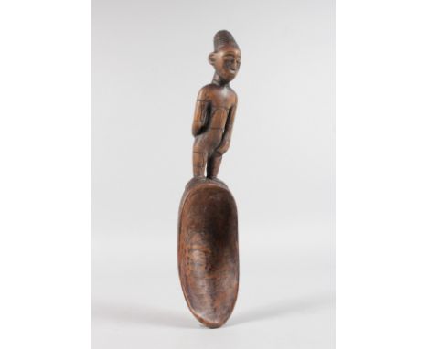 A TRIBAL CARVED WOODEN LADLE. 12ins long.