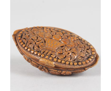 A GOOD COQUILLA NUT CARVED SNUFF BOX carved with a basket of flowers.  7cms long.