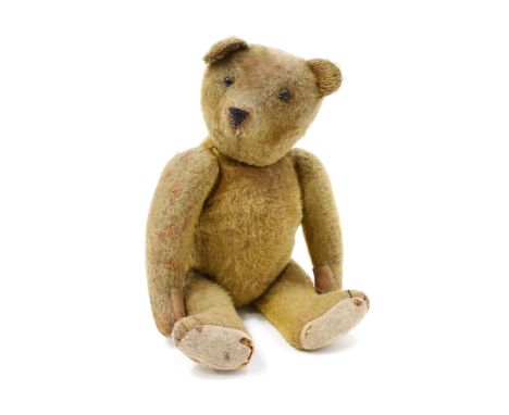 An early 20th century golden mohair jointed teddy bear, black boot button eyes, pronounced snout with horizontally stitched s