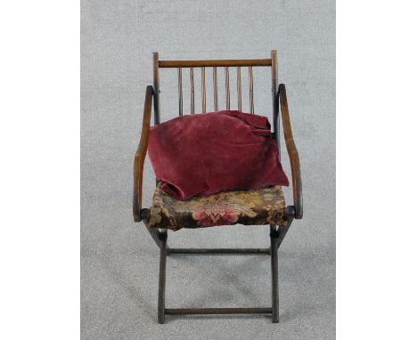 An early 20th century fruitwood folding armchair, with a spindle back, the seat upholstered in a tapestry style fabric. 