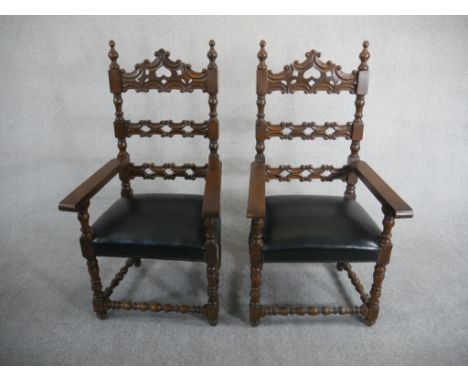 A pair of Spanish walnut ladder back carvers, the back carved with C scrolls over a black leather seat on turned legs joined 