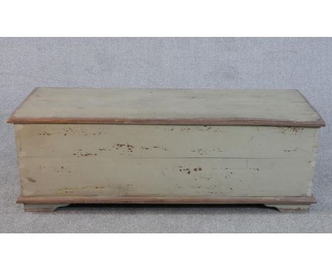 A painted wood trunk of plank construction, the rectangular top with a moulded edge, flanked by two iron handles, on bracket 