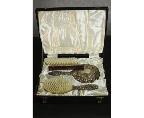 A boxed set of silver repousse scrolling and figural design brushes, mirror and comb. Hallmarked: B&amp;Co, Birmingham,1975. 