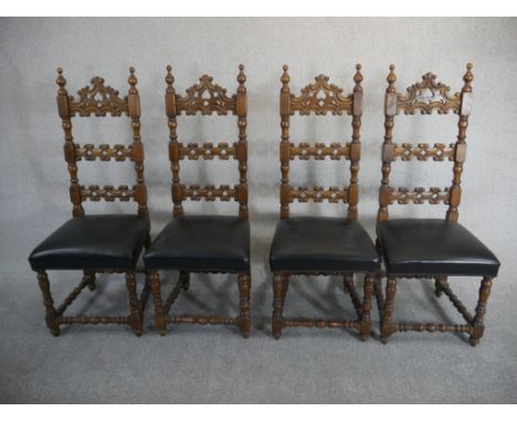 A set of four Spanish walnut ladder back dining chairs, the back carved with C scrolls over a black leather seat on turned le