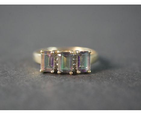 A 9 carat yellow gold mystic topaz and diamond three stone ring, set with three rectangular emerald cut mystic topaz with a c