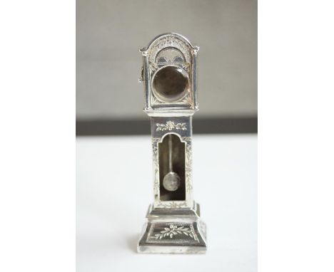 An engraved miniature white metal (tests as silver) grandfather clock watch case with moving pendulum. Engraved floral detail