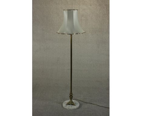 A 20th century brass standard lamp, with a cast tri-form base on a circular white marble plinth, with a shade. H.170cm. 