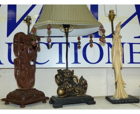 An oriental carved hardwood dragon table lamp; a gilt dog of Fo table lamp; a simulated ivory table lamp