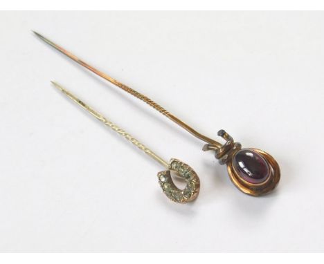 STICK PINS. A Victorian carbuncle stick pin & a paste set horseshoe stick pin. Longest, 8cm.  Please note that all items in t