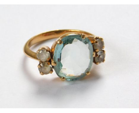 AQUAMARINE RING. A Sri Lankan yellow metal ring, set an oval aquamarine between white sapphires. Aquamarine measures 1.2 x 1c
