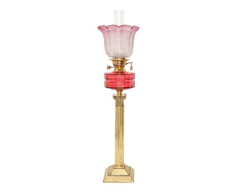A brass Corinthian column oil lamp, c1900, with faceted cranberry glass fount and brass duplex burner, etched cranberry glass
