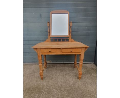 A C.1900 pine dressing table having a swing mirror with an arched pediment set into a turned superstructure with a spindle ga