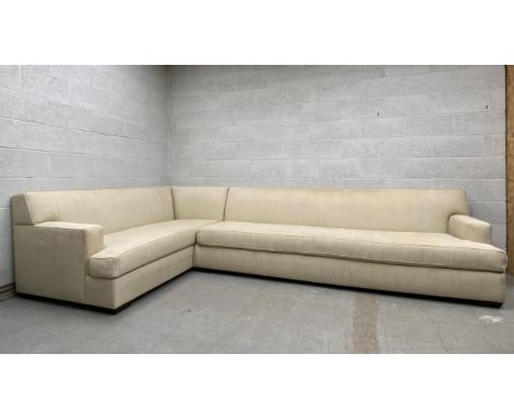 A large contemporary corner sofa having a square stepped back and arms over an L-shaped cushioned seat upholstered in a beige