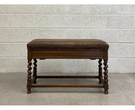 An early 20th century Jacobean style oak stool having a hinged brown velour upholstered stuffover seat opening on to a storag