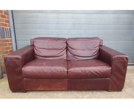 A contemporary Italian maroon leather two seater sofa having a square cushioned back arms and seat raised on short bracket su