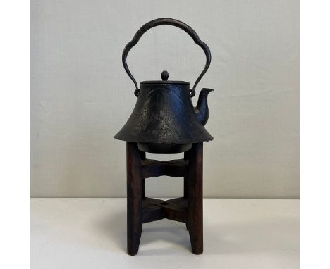 A 19th century Japanese cast iron Tetsubin or kettle having an arched and shaped swing handle over a bell shaped lidded body 