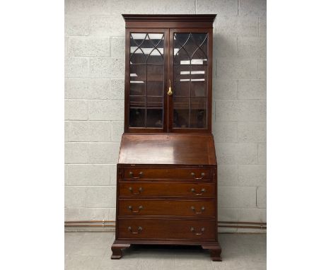 A late 19th century Georgian style mahogany bureau bookcase having a moulded cornice over two glazed cabinet doors opening on