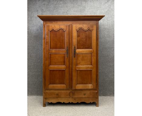 A 19th century French cherrywood armoire having a moulded cornice with two shaped panel doors over two short drawers raised o