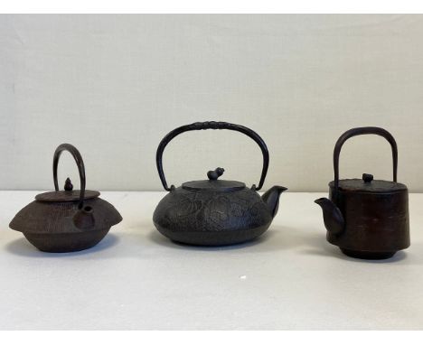 A collection of three 19th century and later Japanese cast iron Tetsubin to include one with an arched swing handle on a lidd