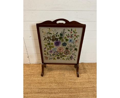 A glass fronted mahogany fire screen with a floral tapestry insert 