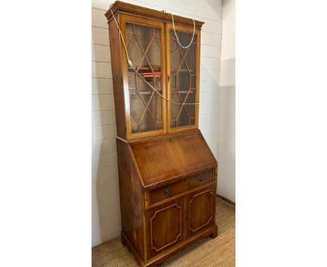 A yew bureau bookcase comprising of a glazed two shelf bookcase and a red leather topped bureau with single drawer and cupboa