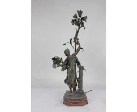 After Moreau, a bronzed metal figural table lamp in the form of a figure posing amongst flowers, holding aloft a wreath, 'Mus