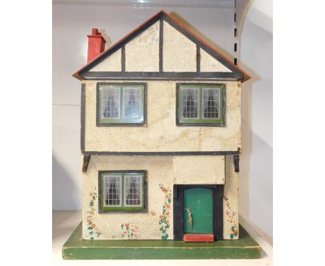 A mid 20thC wooden doll's house, mock Tudor, with a single door, opening to reveal two rooms with period wallpaper, furniture