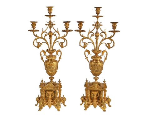 A pair of French gilt metal three light candelabra in Louis XIV taste, 20th century, the waisted urn sockets and drip pans on