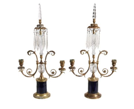 A pair of Regency brass and glass twin light lustre candelabra, circa 1815, each with faceted glass finial above a raised tie