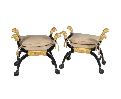 A pair of ebonised and parcel gilt x-frame stools in Regency style, 20th century, each with eagles head finial, 69cm high, 78