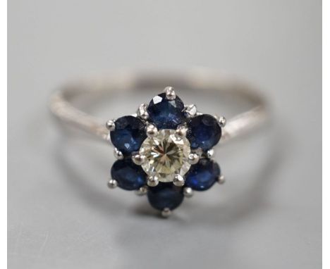 A modern 18ct white gold, single stone diamond and six stone sapphire set flower head cluster ring, size R, gross weight 3.7 