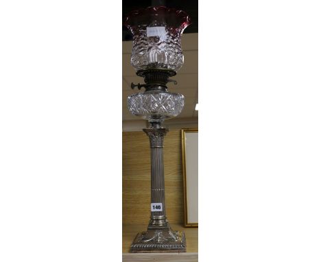 A silver plated oil lamp with cranberry shade