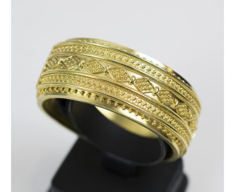 AN ANTIQUE YELLOW GOLD ETRUSCAN STYLE BANGLE c.1870, the wide bloomed gold bangle with bead and wire work decoration. Weight:
