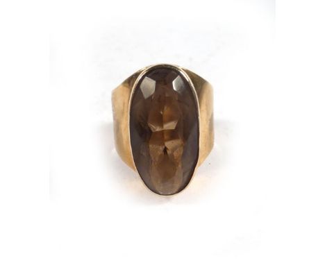 A 9ct yellow gold ring of imposing proportions set centrally with an oval smoky quartz within a raised rubover setting, ring 