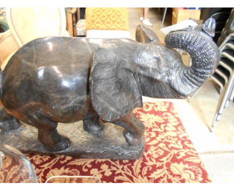 CLARENCE ZANO, a large Springstone carved African elephant with raised spiralled trunk and tail attached to hind , raised on 