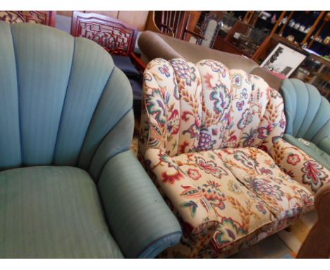 An Art Deco three-piece suite comprising a two-seater sofa and two chairs, each with shell shaped backs, scrolling arms and s