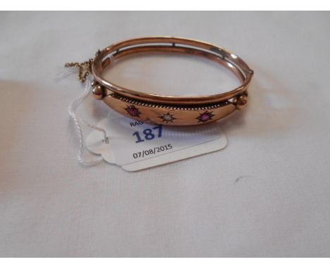 A Victorian 9ct rose gold bangle set with clear and red stones, having safety chain, with the maker's mark 'A&Co' (possibly A