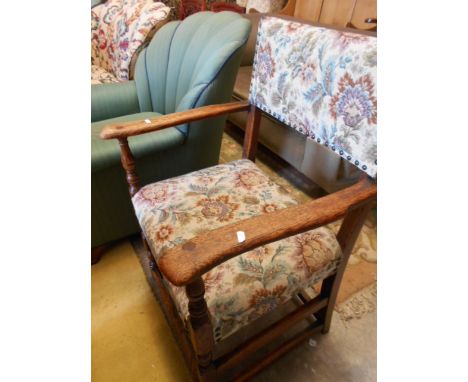 A mid 20th C oak framed open armchair with floral tapestry and studded back and seat, shaped arms and raised on turned cup an