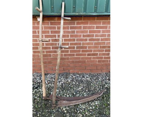 A pair of vintage scythes with wooden handles.