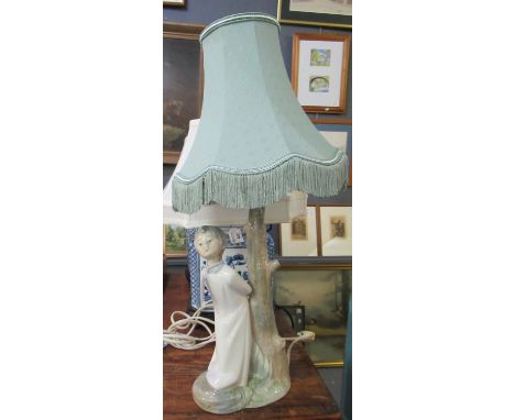 Spanish porcelain table lamp in the form of a young choir boy, standing by a tree stump with shade. (B.P. 21% + VAT) 