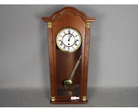 A modern Hermle Vienna style wall clock with key and pendulum.