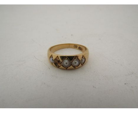 A gold ring set with seed pearls (one missing) stamped 18, size O, 4.9g 