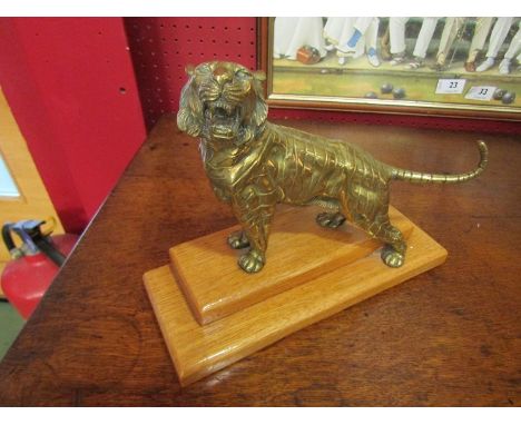 A late 19th Century polished brass sculpture of a tiger, mounted on a light oak stand, 23cm long 