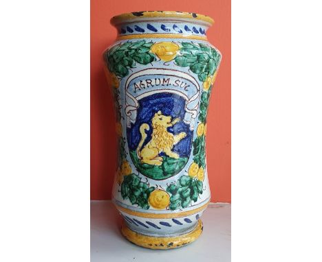 An antique pottery albarello of waisted form, decorated with a heraldic shield surrounded by a laurel wreath - 'Agrum Suc',  