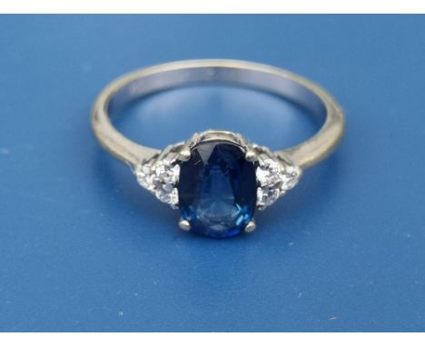 A modern sapphire &amp; diamond set 18ct gold ring, the oval sapphire fanked by six small diamonds - '750'  - the shank yello