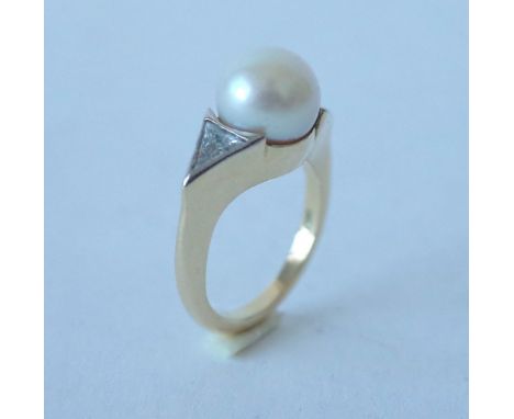 AN 18CT GOLD, DIAMOND AND CULTURED PEARL RINGMounted with the cultured pearl to the centre, between two triangular cut diamon